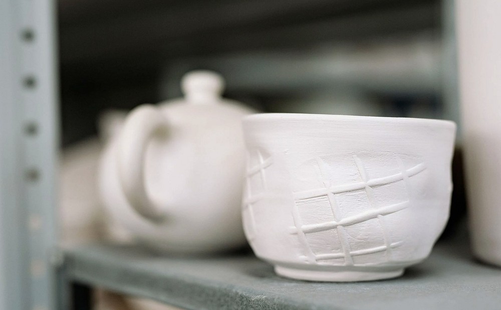 White handmade clay pottery with unique textures displayed on shelves.